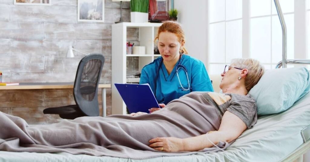 A nurse providing palliative care to a senior woman lying in bed, illustrating the difference between palliative care, hospice care, and home care in a home-like setting.