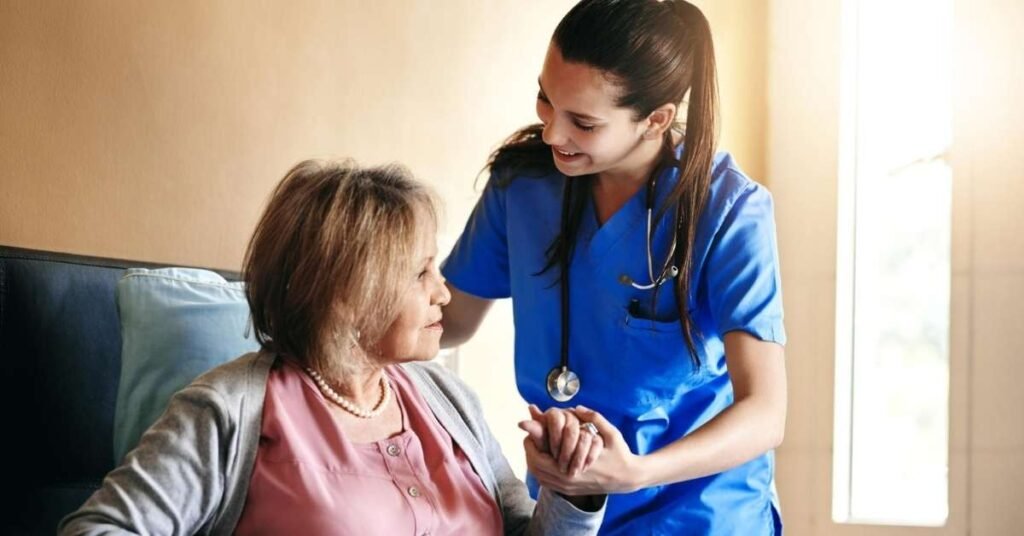Home nurse holding a senior woman’s hand during a supportive home visit, illustrating the difference between home health nursing vs home care.